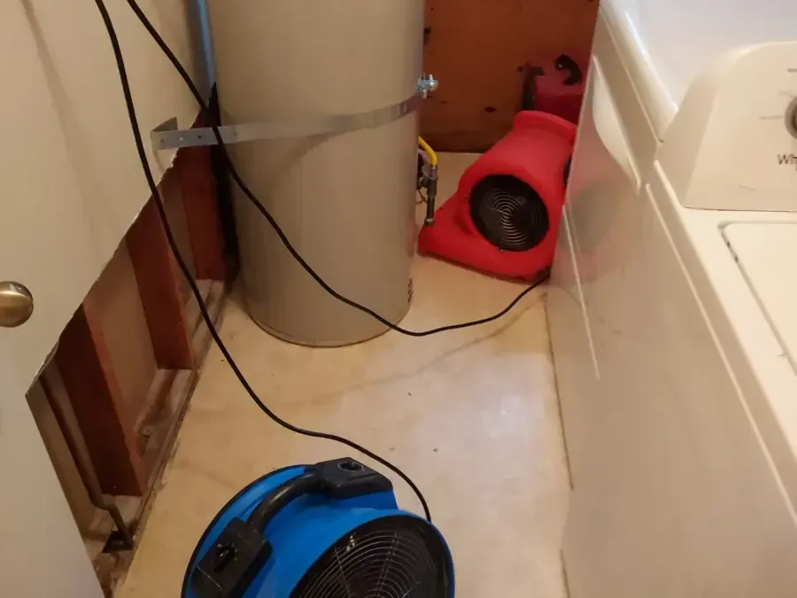 Air movers on a laundry floor beside a washing machine and water heater
